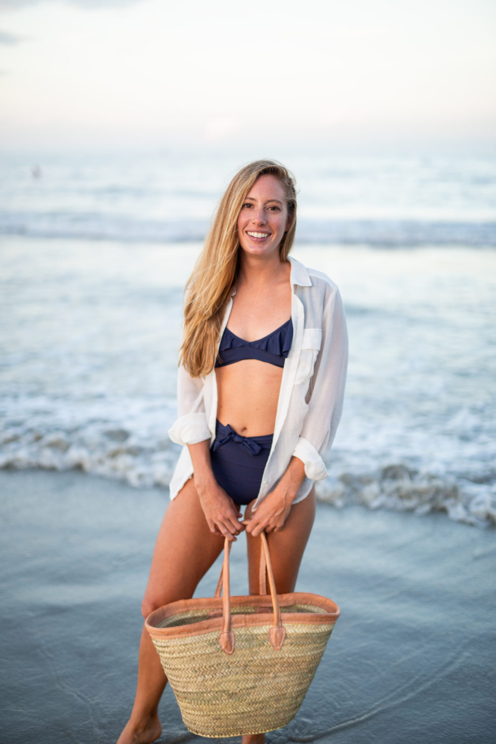 What to Pack in a Beach Bag: 20 Beach Essentials, Wearing Navy High Waisted Swimsuit, White Linen Shirt and Woven Straw Beach Bag | Sunshine Style